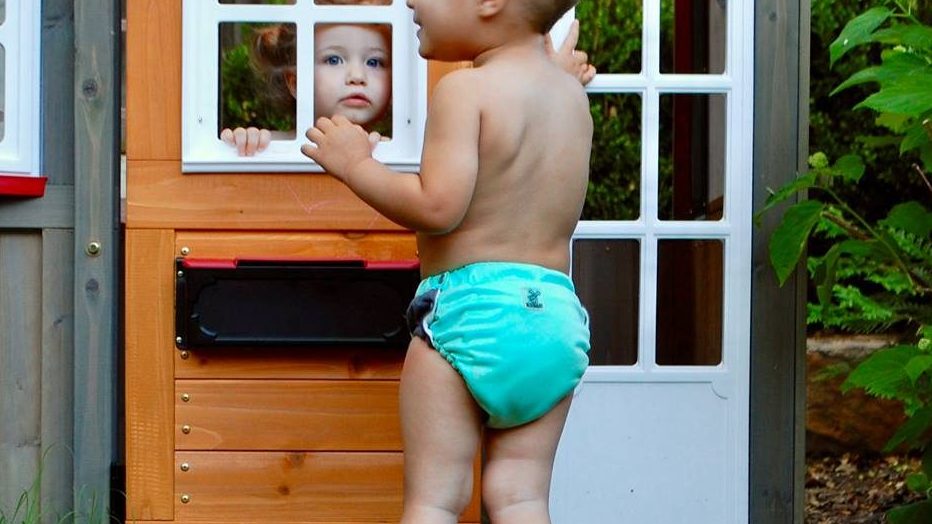 boy in a cloth diaper looking at a girl through a door window